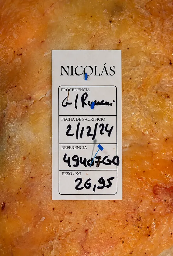 Etiqueta de trazabilidad de Asador Nicolás sobre una pieza de vacuno madurado, con información de procedencia, sacrificio y peso.